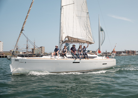 Duel sailing through Portsmouth Harbour with smiling participants waving on a yachting taster